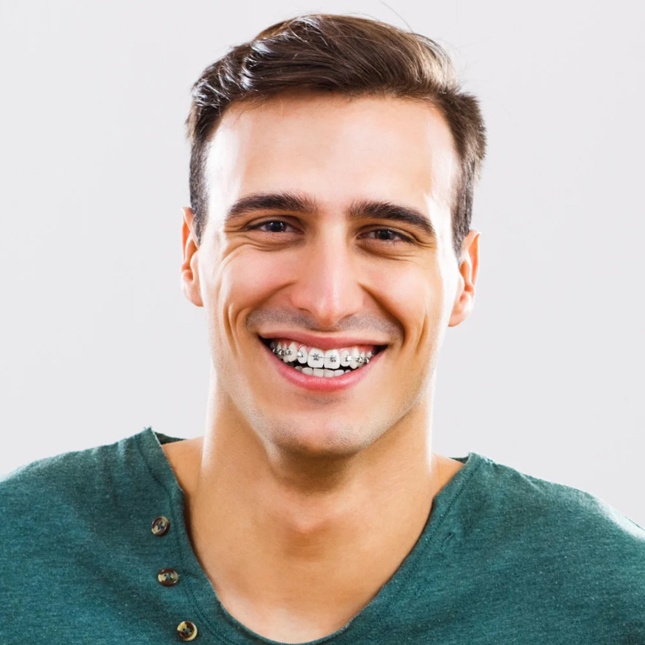 Smiling man with braces wearing green shirt against white background
